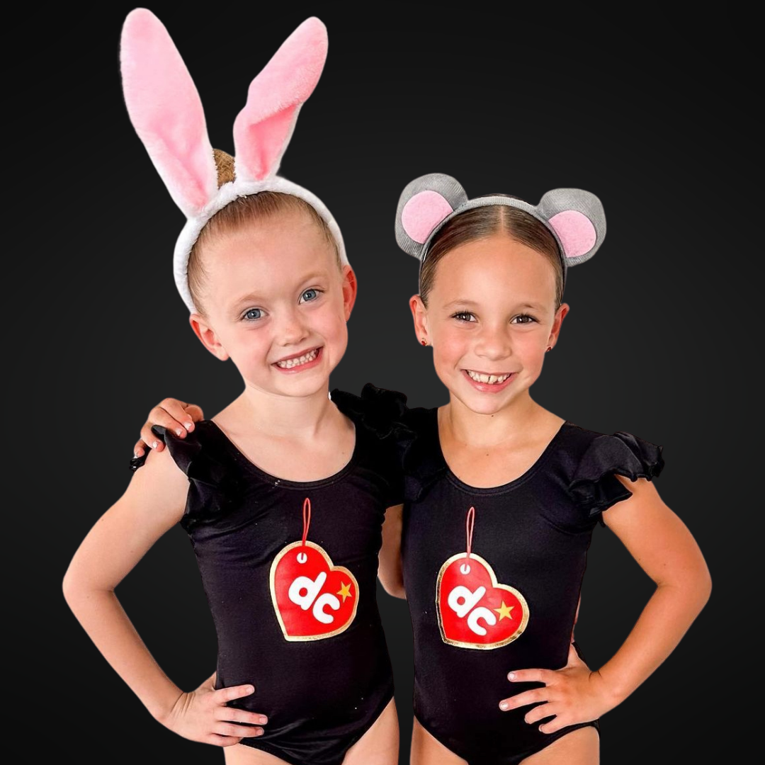 Image of four girls wearing personalized fall dance leotards with ruffle twirl skirts, posing with arms wrapped around each other and big smiles, part of the Leotard Boutique's latest collection.